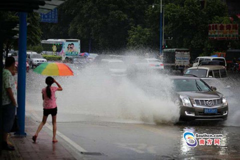 7月21日，广州下起雷暴雨，暴雨造成不少低洼地区水淹，图为广州大道北一低洼处，一辆行驶而过的车辆溅起了近三米高的水花，一旁的行人纷纷躲避。（南方日报记者 郭智军 摄）